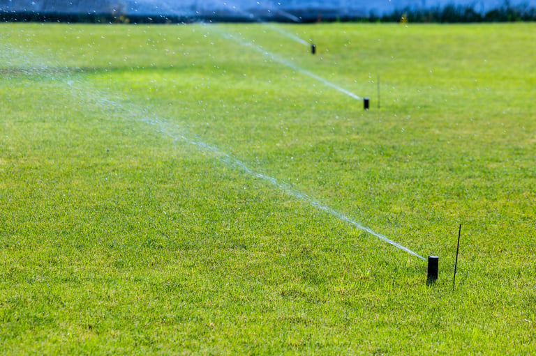 Grassy field with sprinklers actively spraying water